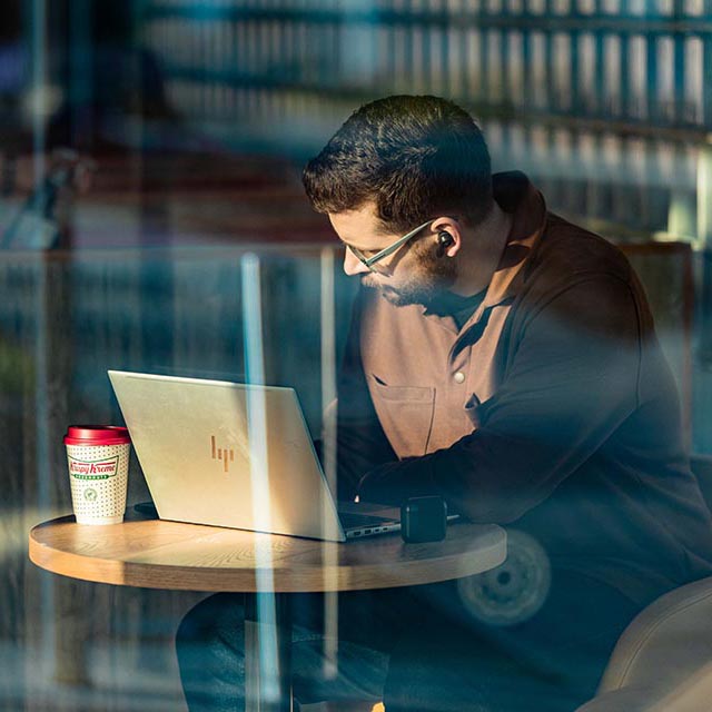 Bearded man writes a note next to laptop