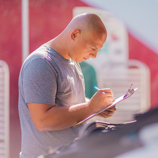 Bald man writes on a clipboard in the sunshine