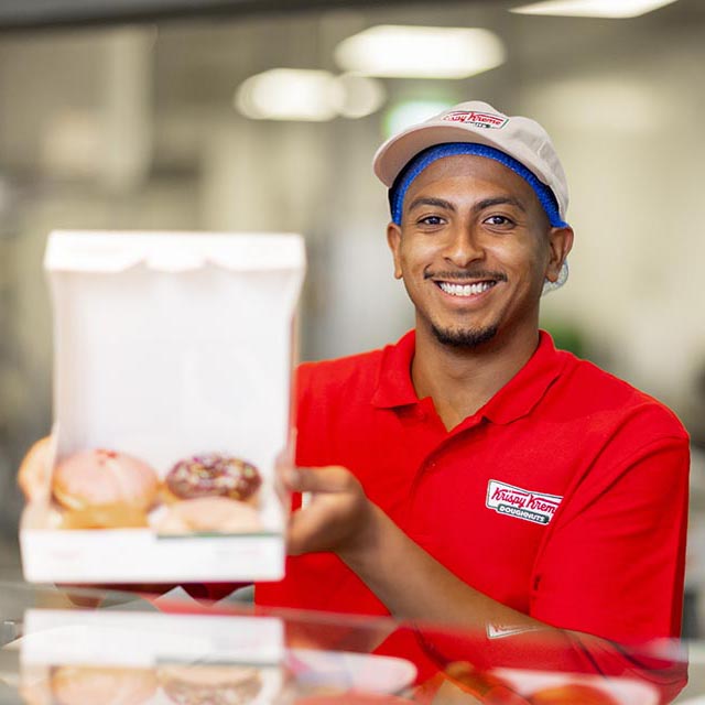 Young smiling man shows a box a donuts