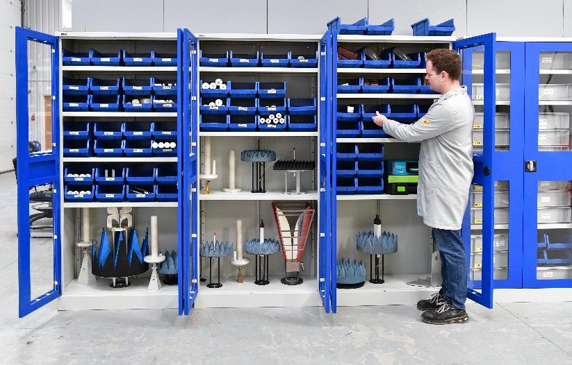 A young man sorts parts into drawers on a shelving unit