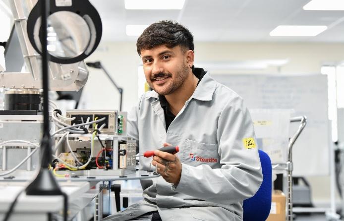 A young technician with a moustache works with a soldering iron