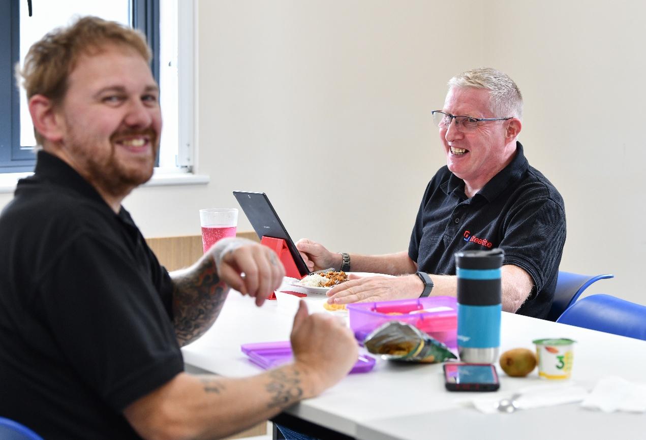 Two colleagues in the canteen share a joke at lunchtime
