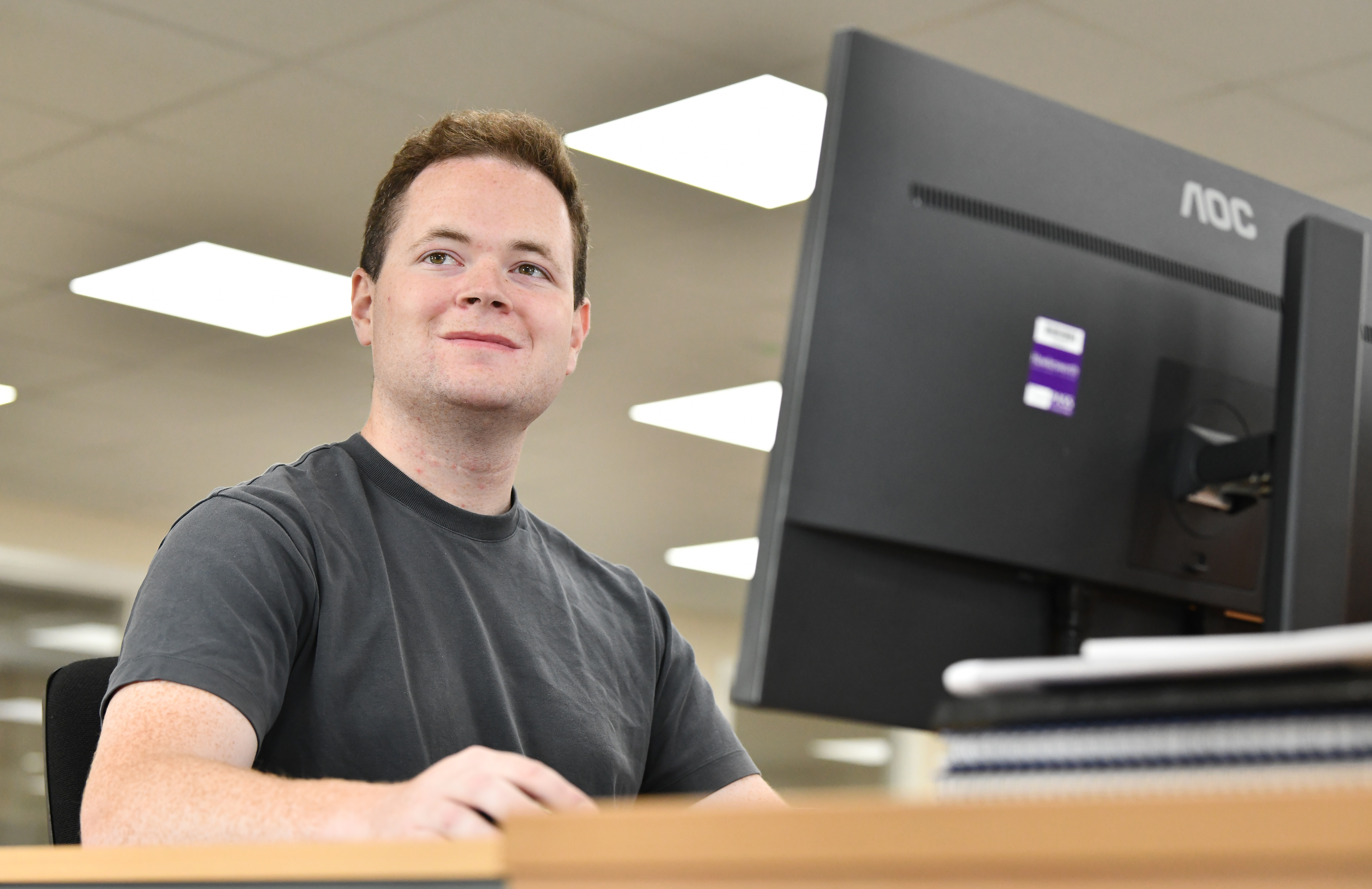 A young man works at a large monitor