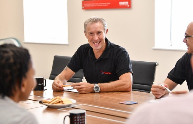 An operations manager sits at a large table and discusses the situation
