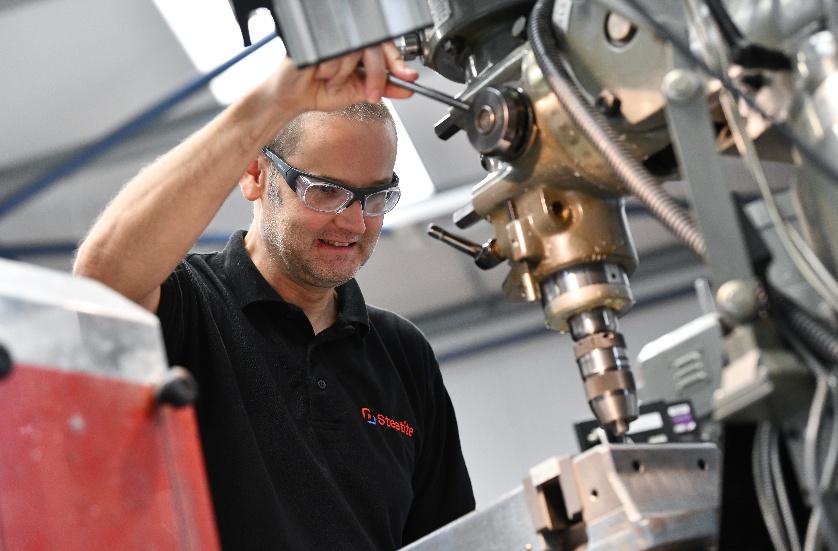 A man in safety glasses operates a precision drill